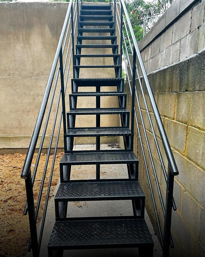 Escada reta externa em estrutura metálica com piso antiderrapante e corrimão duplo